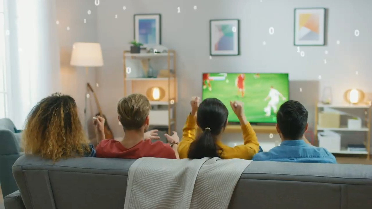 The back of four people sitting on a couch watching a soccer game with binary overlay of 1s & 0s
